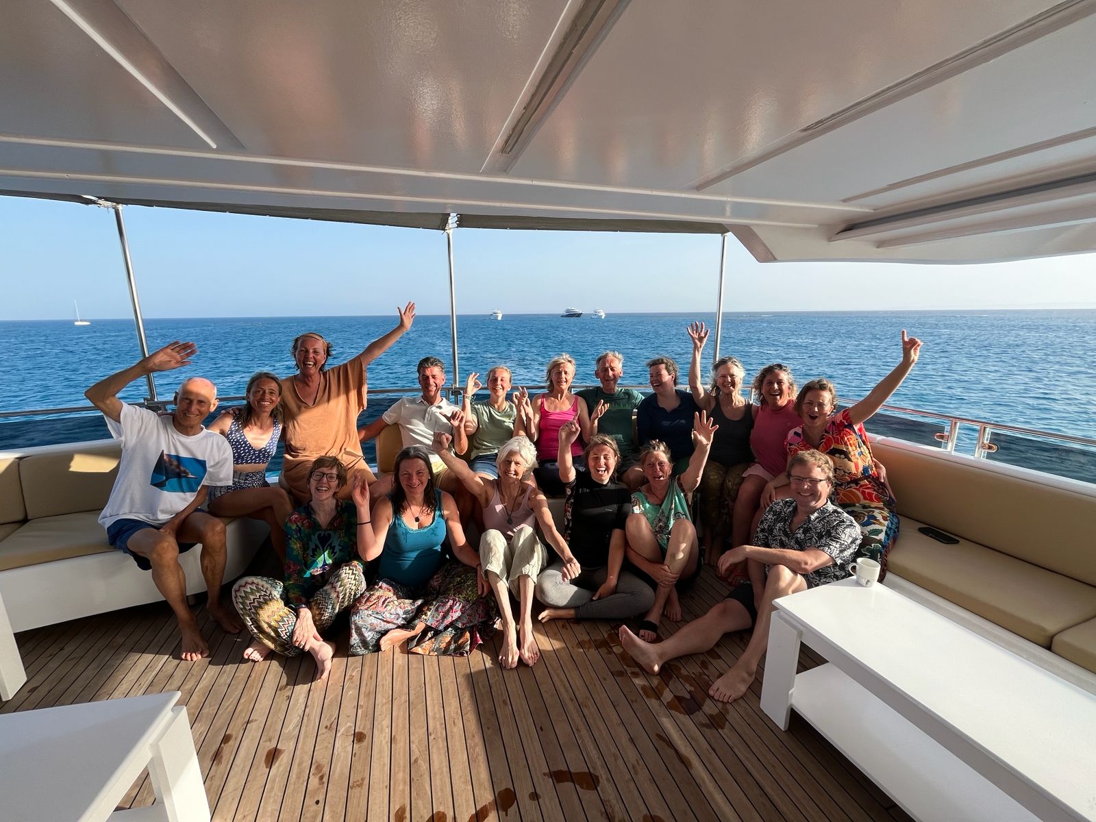 A joyful group of retreat guests waving together on the boat